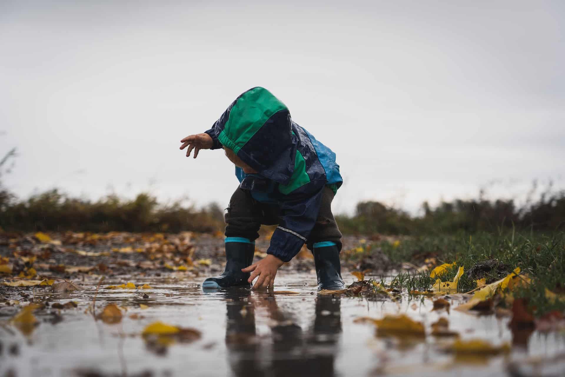 Toddler playing outside in spring puddles