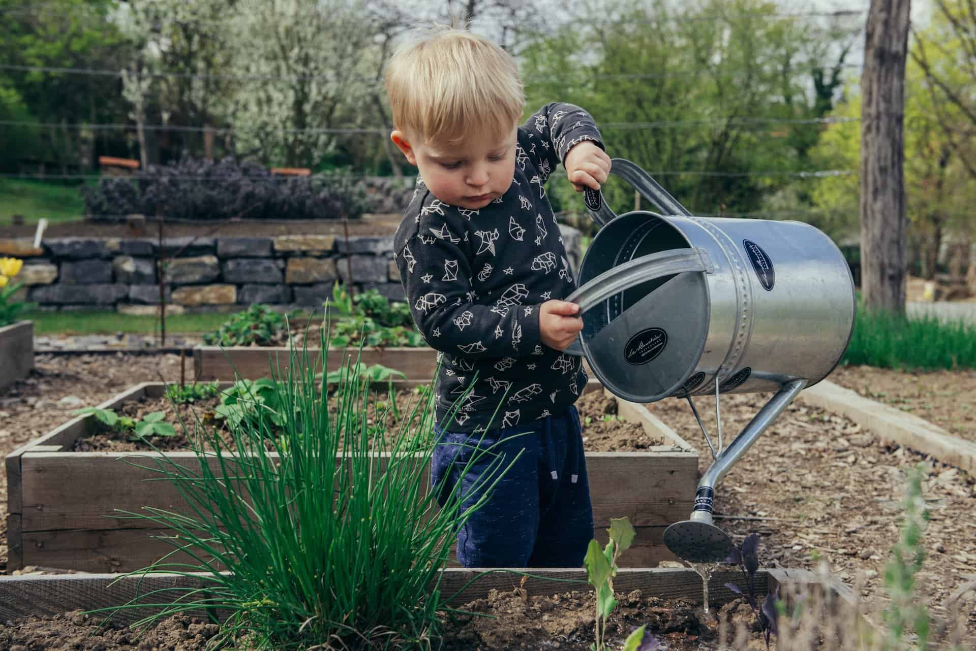 Kid watering the garden plants outside as Earth day activities