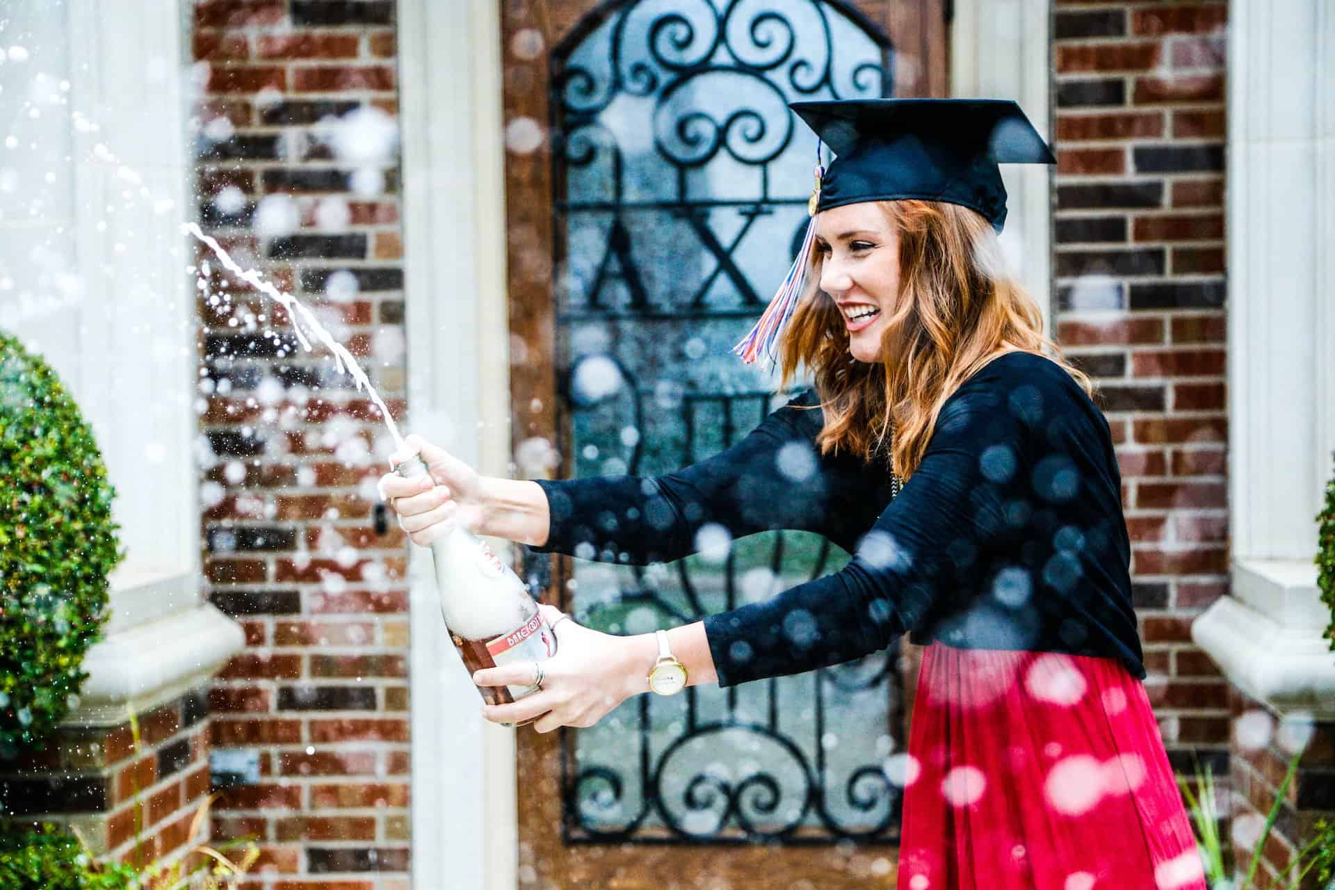 Graduate popping a bottle of sparkling wine