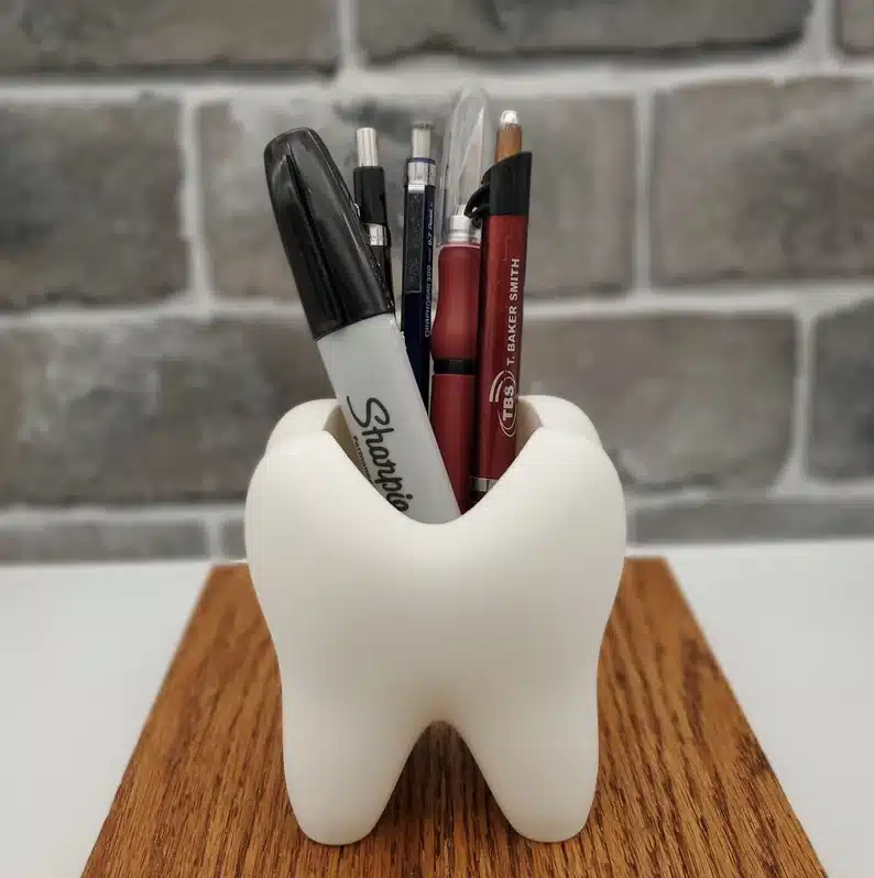 Large white pen holder shaped like a tooth. 