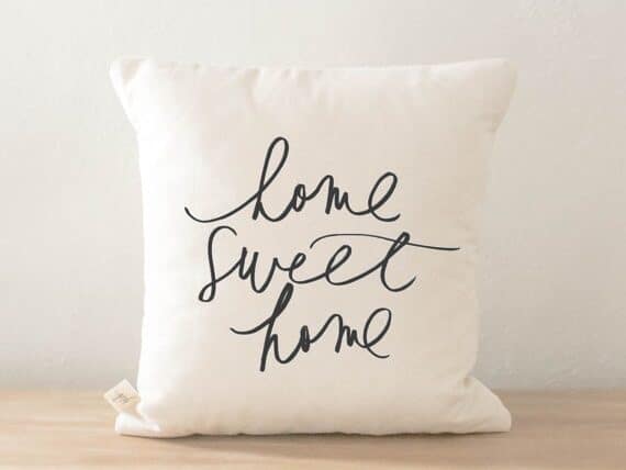 White square pillow with black font that says Home sweet home. 