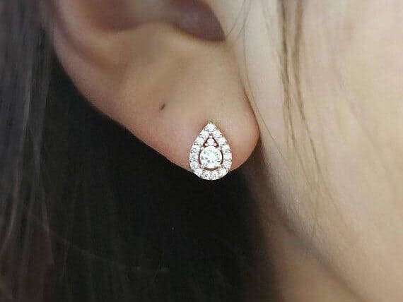 Close up of a woman's ear wearing a tear drop studded earring with diamonds.