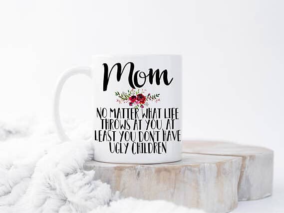 White coffee mug with black font that says "mom no matter what life throws at you least you don't have ugly children"