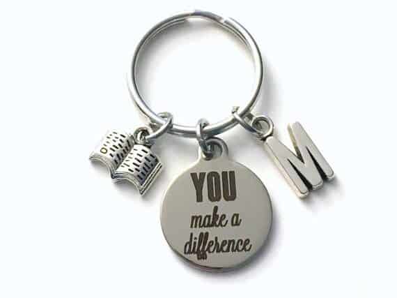 Silver keychain with a open book charm, a round charm that says YOU make a difference, and a letter M charm.