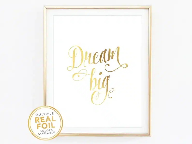 Gold foil frame with a white print with gold font that says Dream big. 