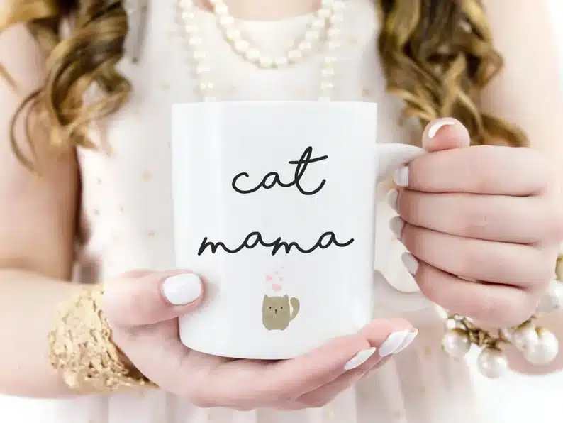 Close up of woman's hands holding a white coffee mug with black font that says 