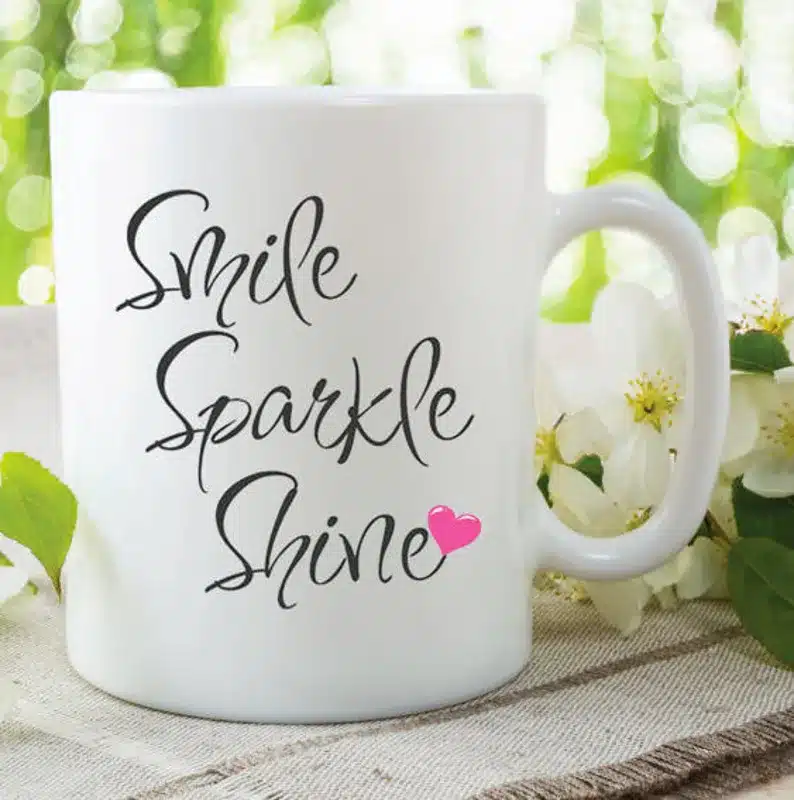 White coffee mug with black font that says Smile sparkle shine. 