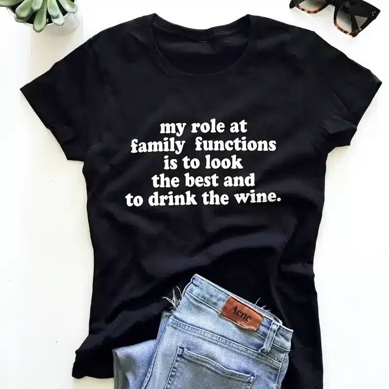 Black t-shirt with white font that says "my role at family functions is to look the best and drink the wine". 