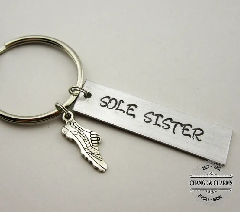 Silver keychain with a rectangle charm that says sole sister with a little shoe charm. 