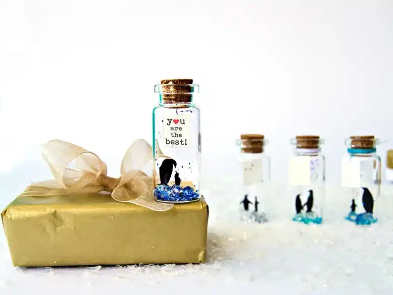 Four personalized vials with little penguins, poems, and sparkles in them. 