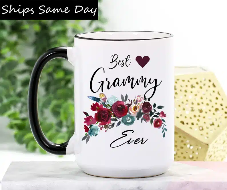 White coffee mug with black handle and black font that says "Best Granny Ever" with red roses on it. 