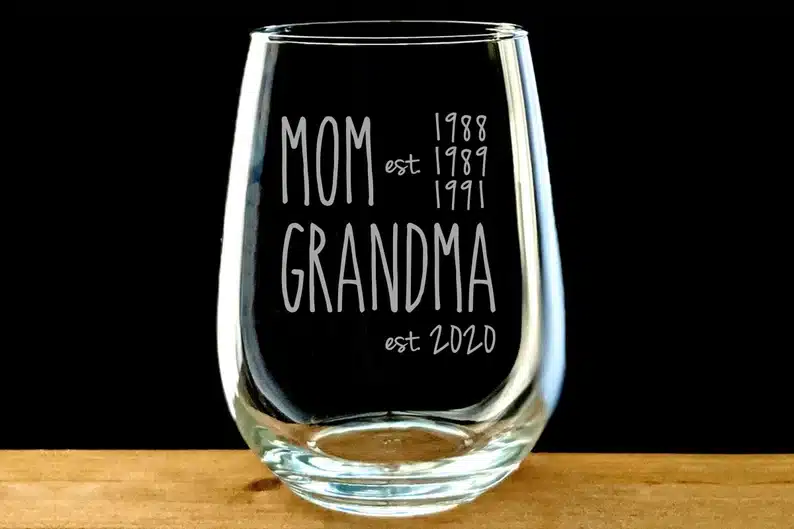 Clear stemless wine glass that says Mom est 1988, 1989, 1991. Grandma est 2020 etched in it. 