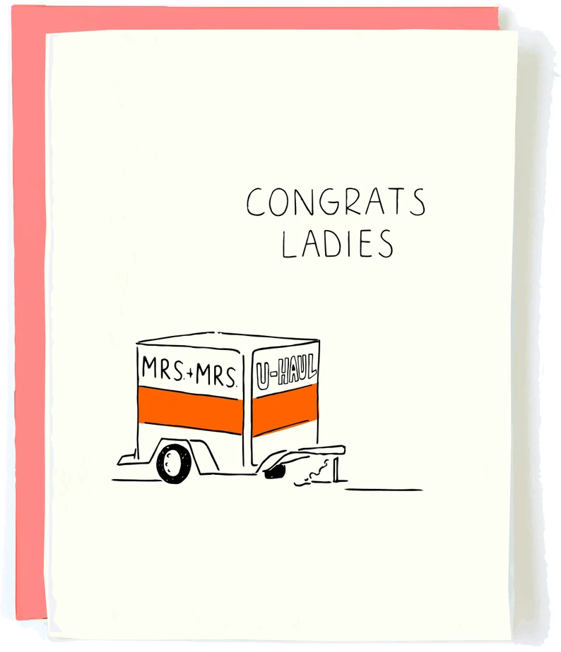 White card with black font that says Congrats ladies. and a drawing of a U-Haul that says Mrs. + Mrs. on it. 