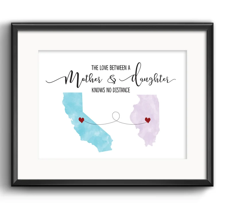 Black framed white print that says The love between a mother and daughters knows no distance, and two different states with a heart on each. 