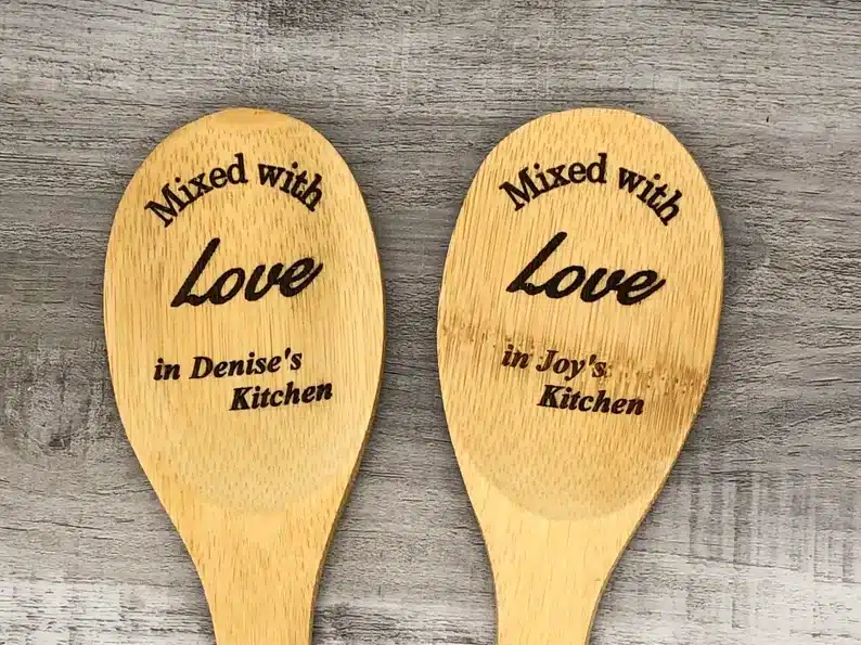 Two wooden spoon ends that says Mixed with love in Denise's kitchen on one and mixed with love in joys kitchen on the other. 
