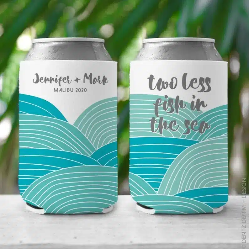Two cans with a can cooler on it, with blue waves on it and grey font that says names of a married couple on one and two less fish in the sea in the other. 