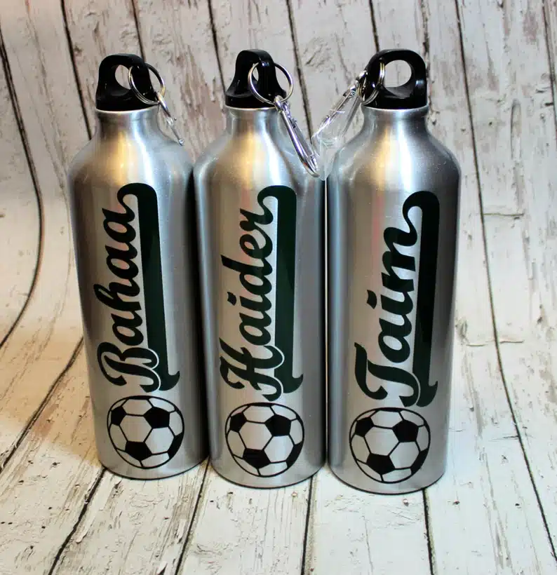 Three silver water bottles with a name and soccer ball on it. 