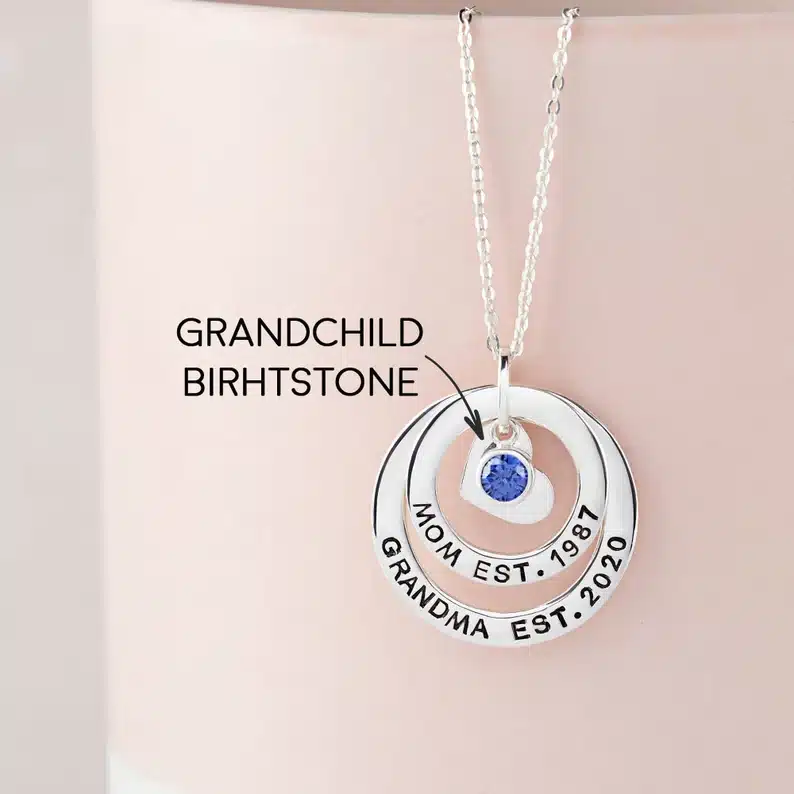 Silver chain with heart charm with blue birthstone with two circle rings around it. 