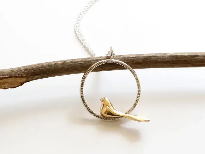 Gold chain with a round charm with a little gold bird on it. 