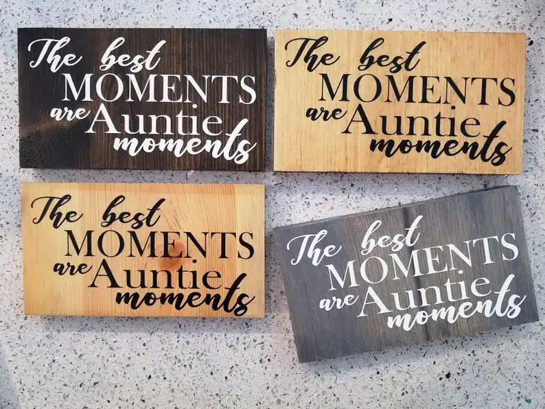 Four wooden signs, one dark, one light, and one grey all with the saying "the best moments are auntie moments". 