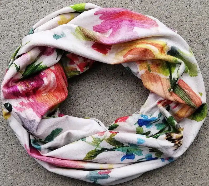 white infinity scarf with pink, orange, green, and blue marks all over it. 