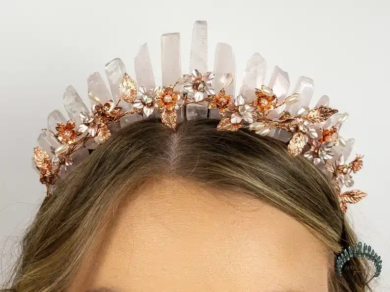 Top of a woman's head showing off a crown mad of crystals and bonze and silver flowers. 