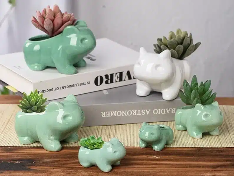 Housewarming Gifts for Geeks: Various shades of green and white succulent planters shaped like the Pokémon Bulbasaur. 