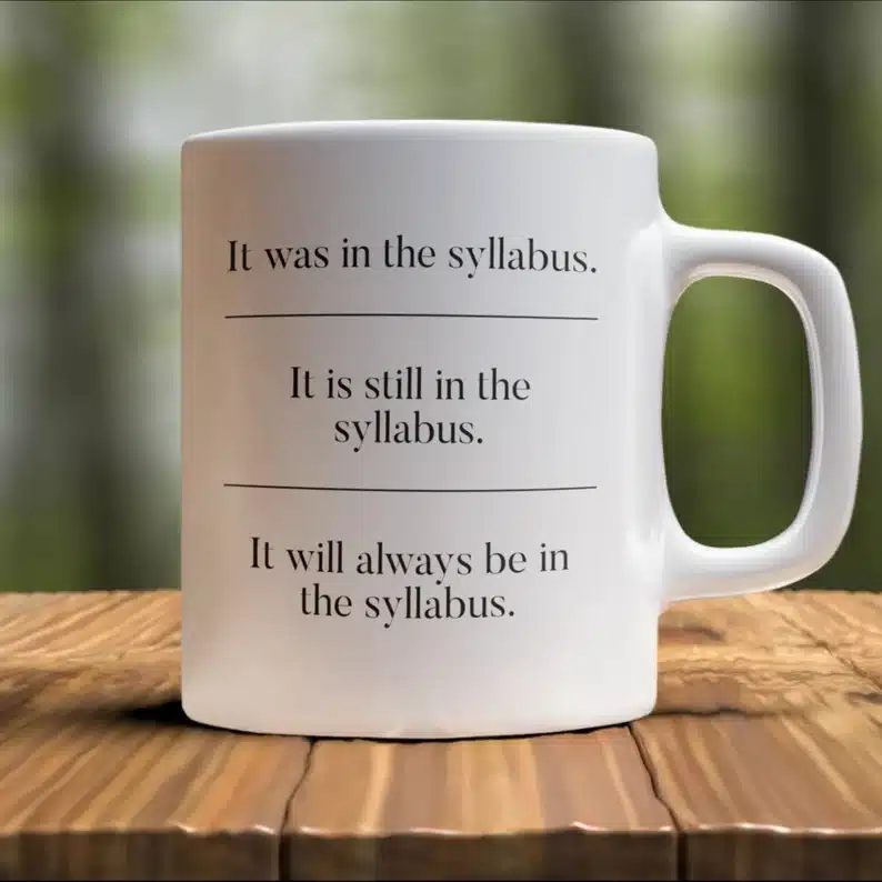 White coffee mug with black font that says "it was in the syllabus. It is still in the syllabus. It will always be in the syllabus"