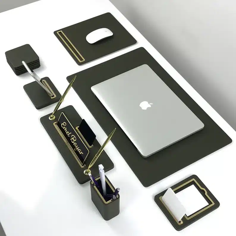 Above view of a white desk with black desk set, mousepad, laptop pad, note pad, pen holder, and more. 