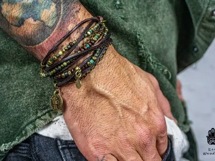 Close up of a tattoo mans wrist with various leather and beaded bracelets. 