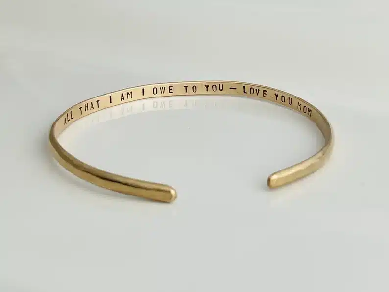 Gold cuff bracelet that says All that I am I owe to you. 