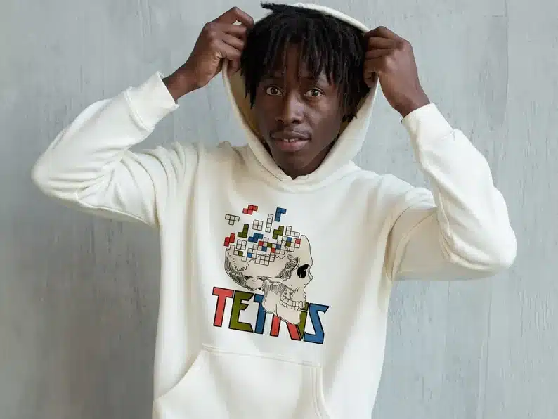 Man wearing a white hoodie with a skull and Tetris pieces coming out of it. 