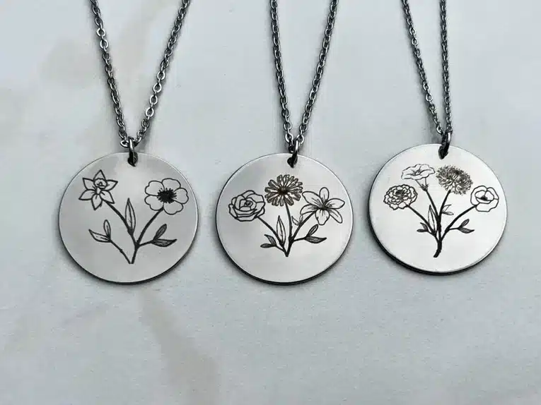 Three silver necklaces each with a round charm each with hand stamped of flowers. 