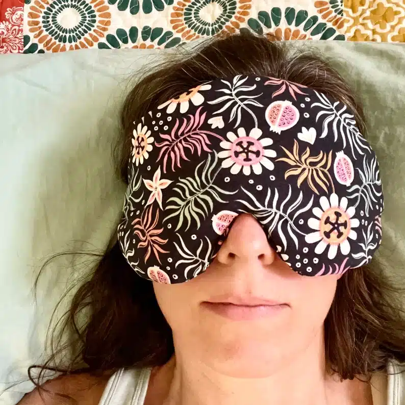 Woman wearing a black eye mask with flowers on it. 