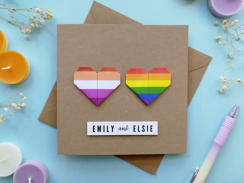 Brown card with two rainbow hearts made of paper on it. 