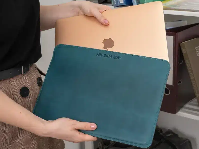 Close up of woman holding a gold MacBook going into a blue sleeve case. 