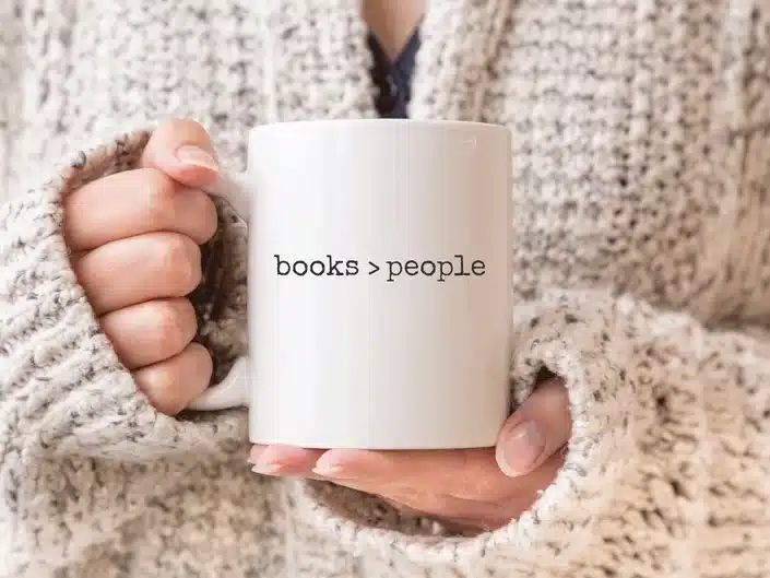 Close up of a women holding a white coffee mug with black font that says "books > people"