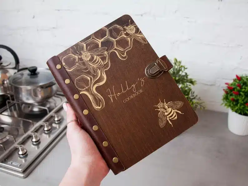 Brown wooden personalized family cookbook with honey bees on it. 