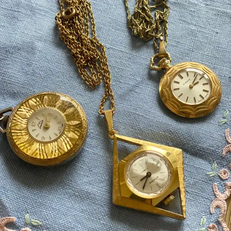 Three gold watch clocks on gold chains. 