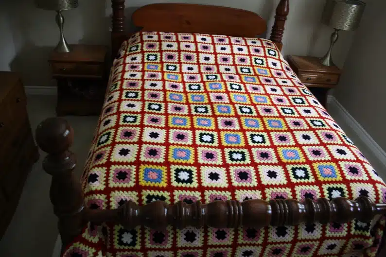 Bed with a hand crocheted afghan. 