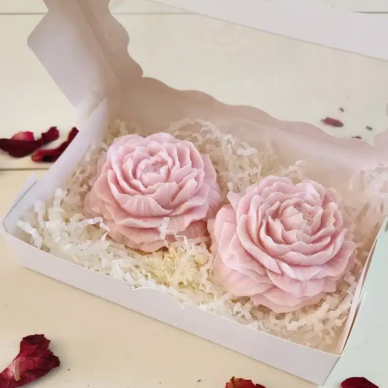 White box with two light pink rose shaped soap. 