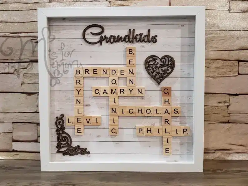 White framed scrabble lettered artwork with grandkids made out to look like a scrabble game. 