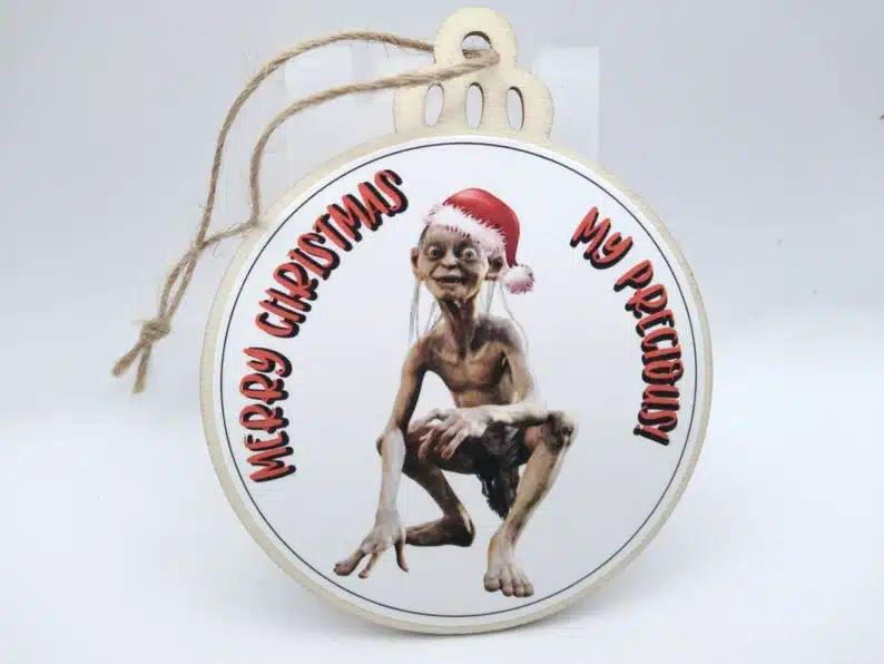 Round Christmas ornament with Gollum on it that says Merry Christmas my precious in red font. 