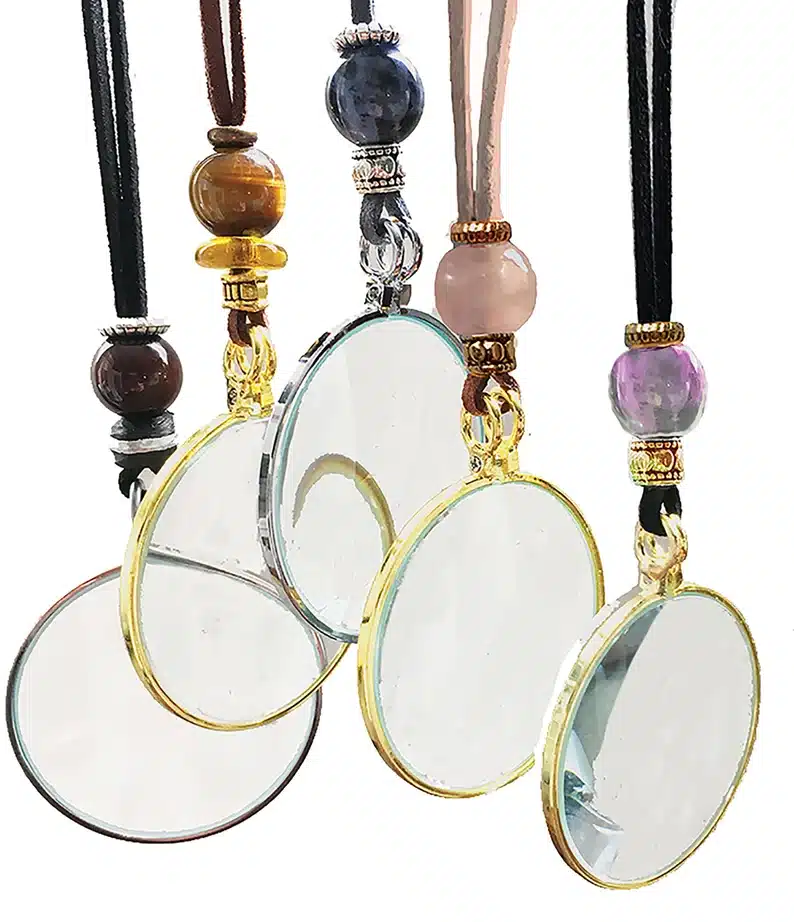 five different magnifying glass necklaces, each with around magnifying at the end and different beads on the strings. 