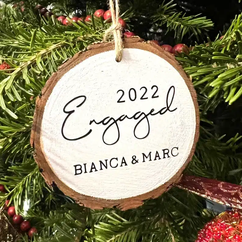 Wooden round ornament with black ink that says 2022 engaged Bianca & Marc. 