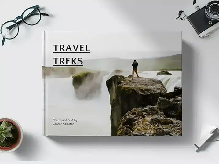 Personalized photo book, white book with cliffs and a waterfall in the background with a man standing on top of the cliff. 