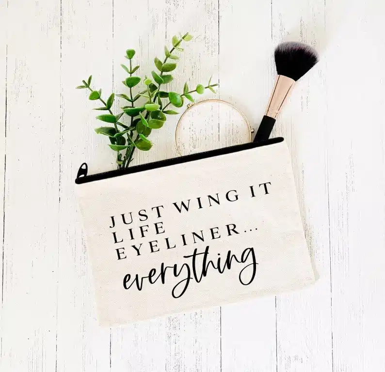 Tan make up bag with black font that says Just wing it life eyeliner...everything. 
