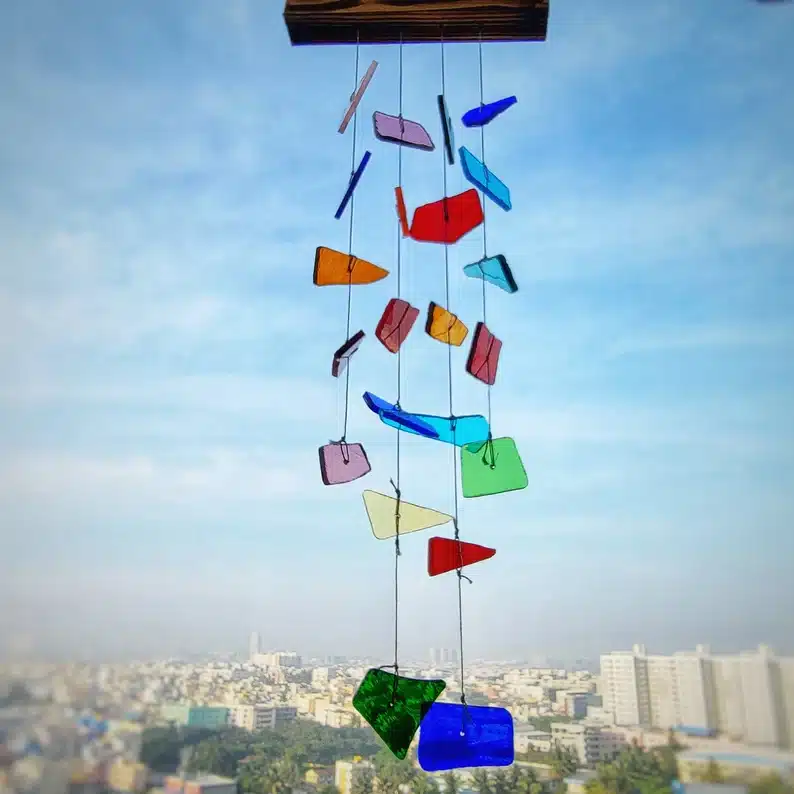 Blue sky with a wind chime shown, with different pieces of plastic colored pieces. 