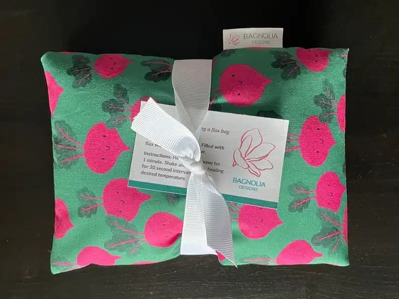 Mother's Day Gifts for Nursing Home Residents -Neck and shoulder rice bag wrapped with a white ribbon. Pattern on bag is green with red radishes all over with smiley faces on radishes. 