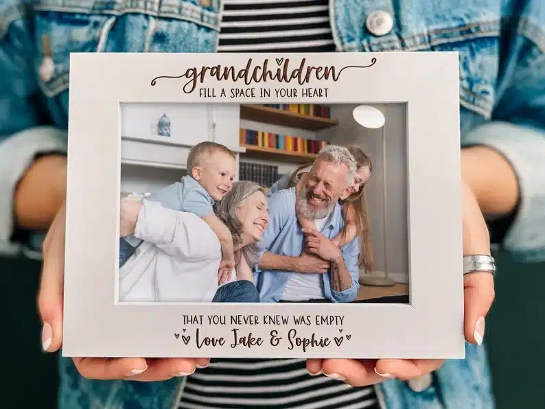 Hands holding a picture frame that says Grandchildren fill a space in your heart. 